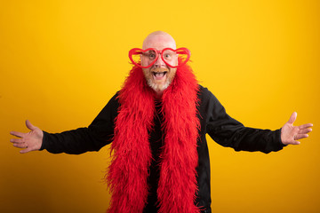 Bald man having fun wearing vibrant red feather boa and heart shaped glasses