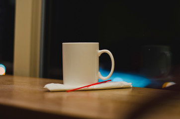 The solo blank coffee cup in the diner next to the window in the late night. 