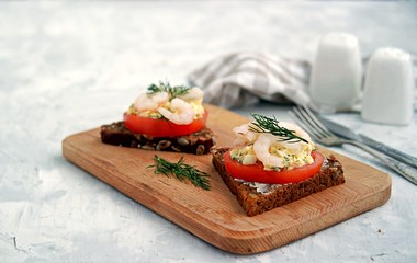 Rye open sandwich with tomato, egg salad and shrimps. Danish cuisine.