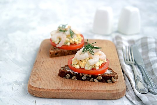 Rye open sandwich with tomato, egg salad and shrimps. Danish cuisine.