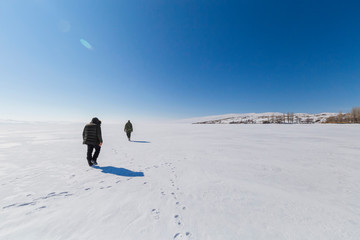 Fototapeta na wymiar Walking people on frozen lake
