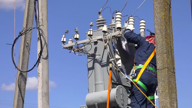 Remont power transformer. Maintenance of overhead power lines. Electrician lineman repairman worker at climbing work on electric post power pole and change transformer.