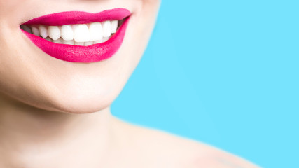 Close-up of a smiling woman with healthy white teeth, red lipstick, clean skin. Dentistry concept. Blue background. Copy space. 