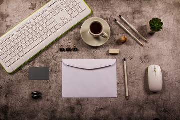 Template desk mockup with computer keyboard blank envelope, notepad and cup of coffee with stationery in gray background. View from above. Flat lay. Layout for the designer.