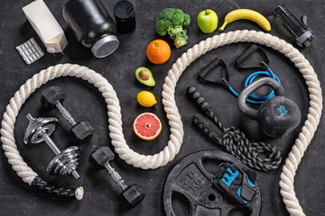Sports equipment and healthy nutrition on a black background. Top view. Motivation