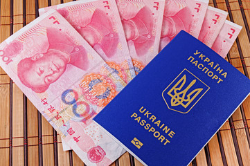Ukrainian passport and yuans on background of bamboo mat