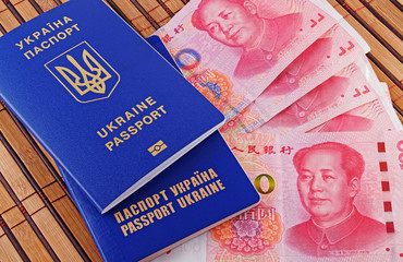 Ukrainian passport and yuans on background of bamboo mat