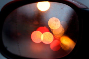 City traffic lights at night,  abstract blurry circles in rear view mirror