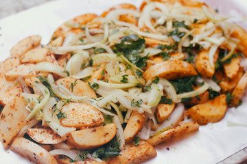 Raw potato sliced on a baking foil. Prepared for cooking with spices, vegetables, onions, herbs. Cooking process. Traditional cuisine.