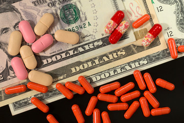 Tablets, pills, capsules on dollars background. Concept of expensive therapy.