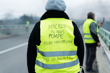Une gilet jaune de dos avec une inscription pour macron - Manifestation en France