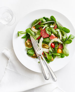 salad dish with tomatoes lattuce chestnuts on a white table