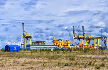 Equipment and mechanisms for a container terminal against a cloudy sky.