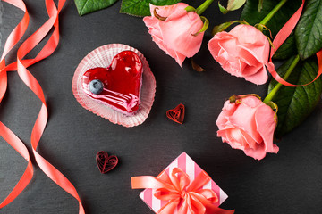 Heart shaped dessert on a slate board with roses and gift, romantic evening, overhead flat lay