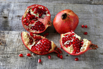 Fresh pomegranate seeds and pomegranate slices on wooden background