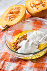Raw washed millet, rice and raisins in a glass pan in the process of cooking milk pumpkin porridge