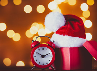 Vintage alarm clock with Santa Claus hat, box and Fairy Lights on background