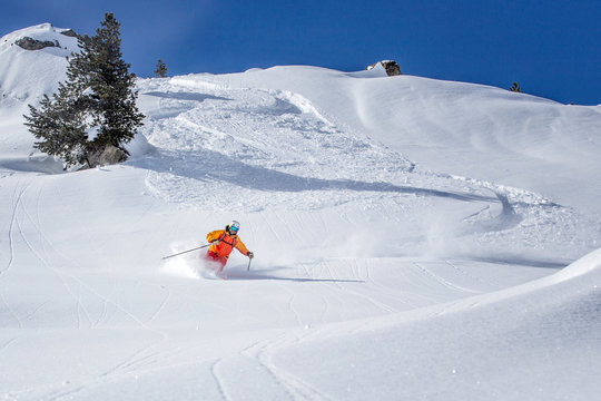 freeride skier skiing downhill through deep powder snow