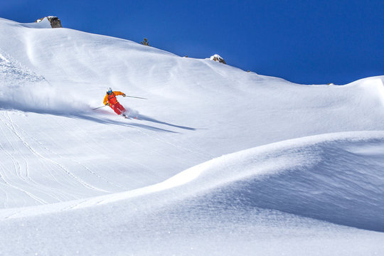 freeride skier skiing downhill through deep powder snow