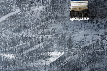part of the brush in black and white paint on the background of a concrete painted gray background in the upper right