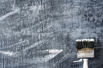 part of the brush in black and white paint on a background of a concrete painted gray background from the top right to the bottom