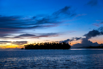 Naklejka na ściany i meble Orange-blue sunset over little island in the Pacific ocean, French Polynesia.