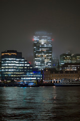 Fototapeta na wymiar Commercial buildings on the bank of river thames in the mid of rain and snow