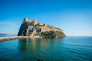Scenic morning view of the dramatic stone fortress of Aragonese Castle looming from its ancient mountaintop perch above the Mediterranean island of Ischia, Italy