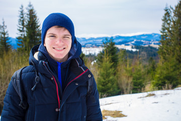 Fototapeta na wymiar Happy young boy on top of mountain with snow covered trees admiring beautiful valley view