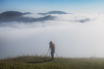 Obraz premium tourist in the mountains. photographer takes a sunrise in the mountains