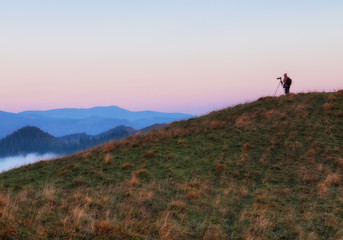 Obraz premium tourist in the mountains. photographer takes a sunrise in the mountains