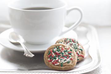 Christmas photograph of a large white coffee cup on a silver tray with two Christmas cookies