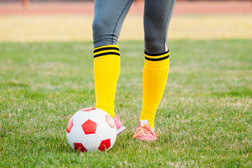 woman soccer player kicks ball on football field