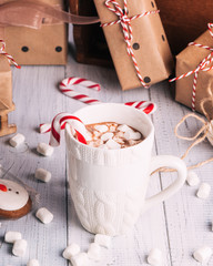 Obraz na płótnie Canvas Cup of cocoa or chocolate on wooden Christmas background. Winter hot chocolate drink with marshmallows, snowman and a fir-tree cookies, candy canes