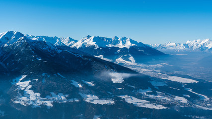 Fototapeta na wymiar snow covered mountains with blue sky and som mist