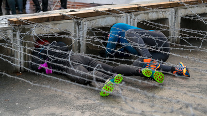 Athlete crawling under barbed wire at an obstacle course race 
