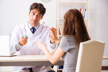 Fototapeta premium Young woman visiting male doctor ophthalmologist in hospital