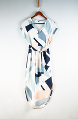 Stylish colorful dress with a geometric pattern. The dress hangs on a hanger on a thick rope. Summer dress in bright colors with a purple, blue, pink pattern.