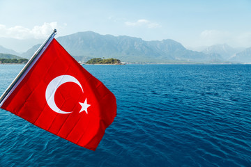 Naklejka premium Turkish flag flying in the wind against the background of the sea and the coast