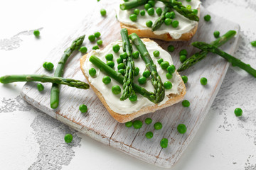 Appetizer bruschetta, toast with Asparagus, Peas and creamy soft cheese. on white board.