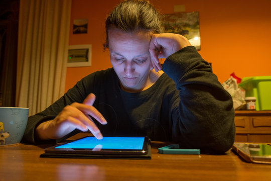 Tired mother taking some time to study on tablet.