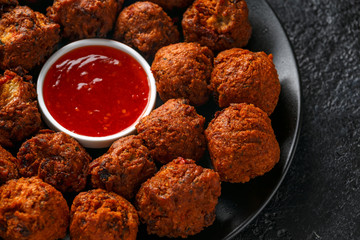 Indian Pakora snack spicy onion, red pepper with chilli sauce in a black plate