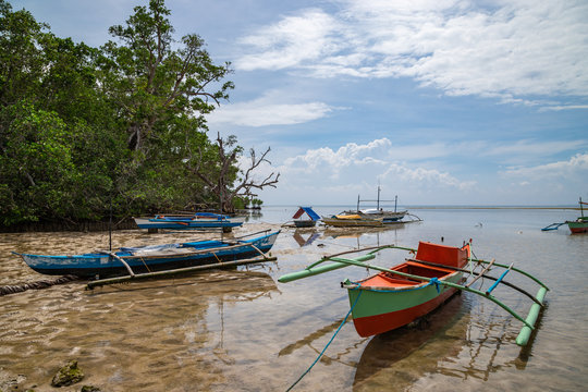 Seashore at Bohol island with low tide and old fisherman boats front view. Philippines.