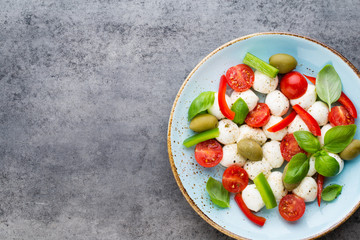Delicious caprese salad with ripe cherry tomatoes and mini mozzarella cheese balls with fresh basil leaves.
