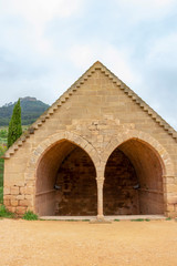 Fototapeta na wymiar The double arched building of Fuenta de los Moros, the Gothic Fountain of the Moors, the ruins of Castillo de Monjardin in the background, at Villamayor de Monjardin Spain