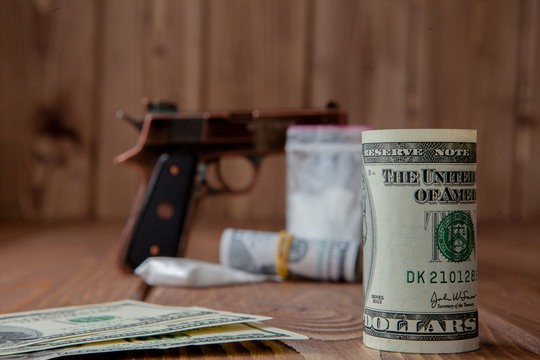 Stack of Money, drugsand a gun on a wooden table, concept about danger and threat of the drug