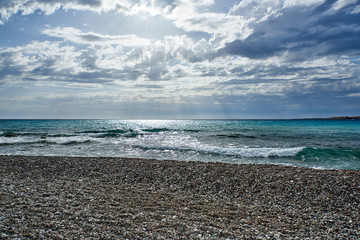 Cyprus. Kissonerga. The sun's rays from the clouds over the pebble beach