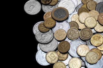 Ukrainian coins with one euro coin isolated on black background. Close-up view. Coins are located at the right side of frame. A conceptual image.