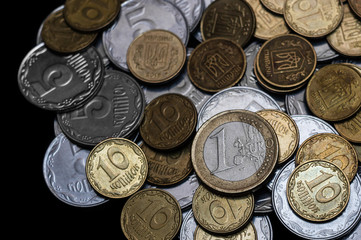 Ukrainian coins with one euro coin isolated on black background. Close-up view. Coins are located at center of frame. A conceptual image.