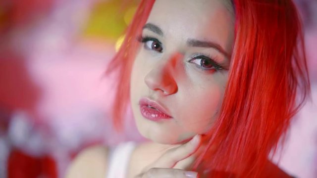 alluring caucasian woman with dark eyes and red hair is looking at camera sensually, touching her face